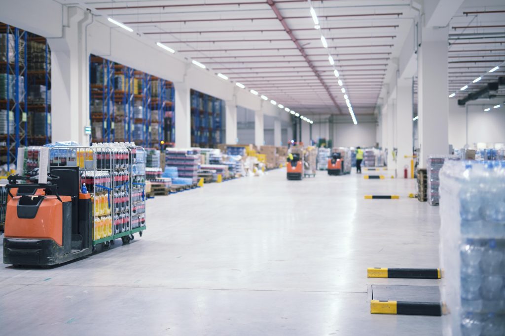 warehouse industrial building interior with people forklifts handling goods storage area min
